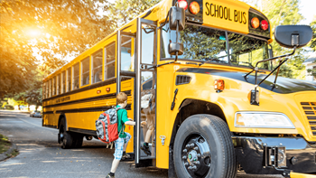 A child is getting off a yellow school bus.